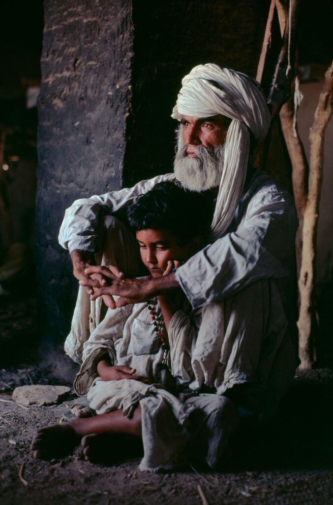 father with turban and beard seated with arms around son